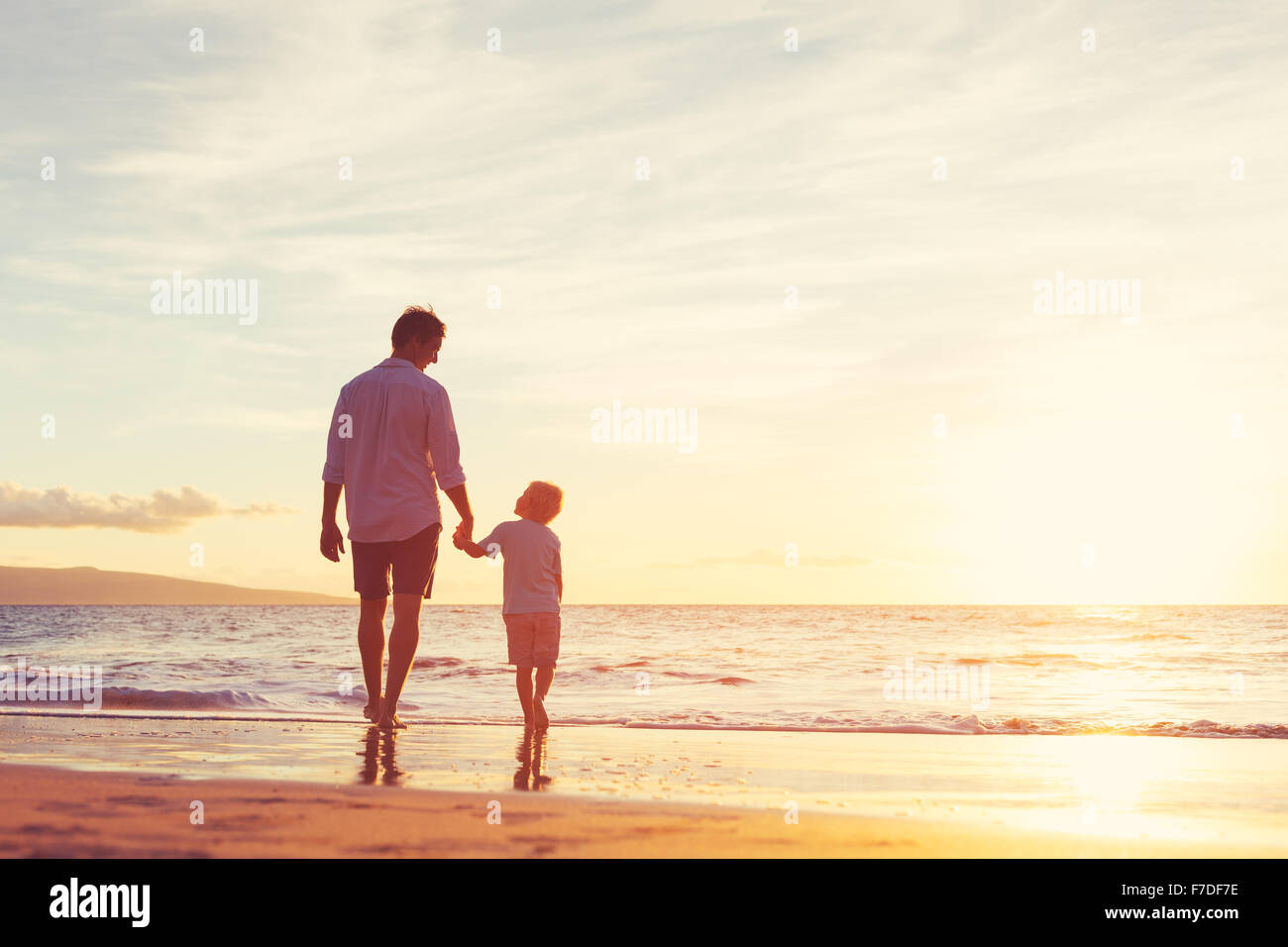 Father and Son Walking Together on the Beach at Sunset. Fatherhood Family Concept Stock Photo