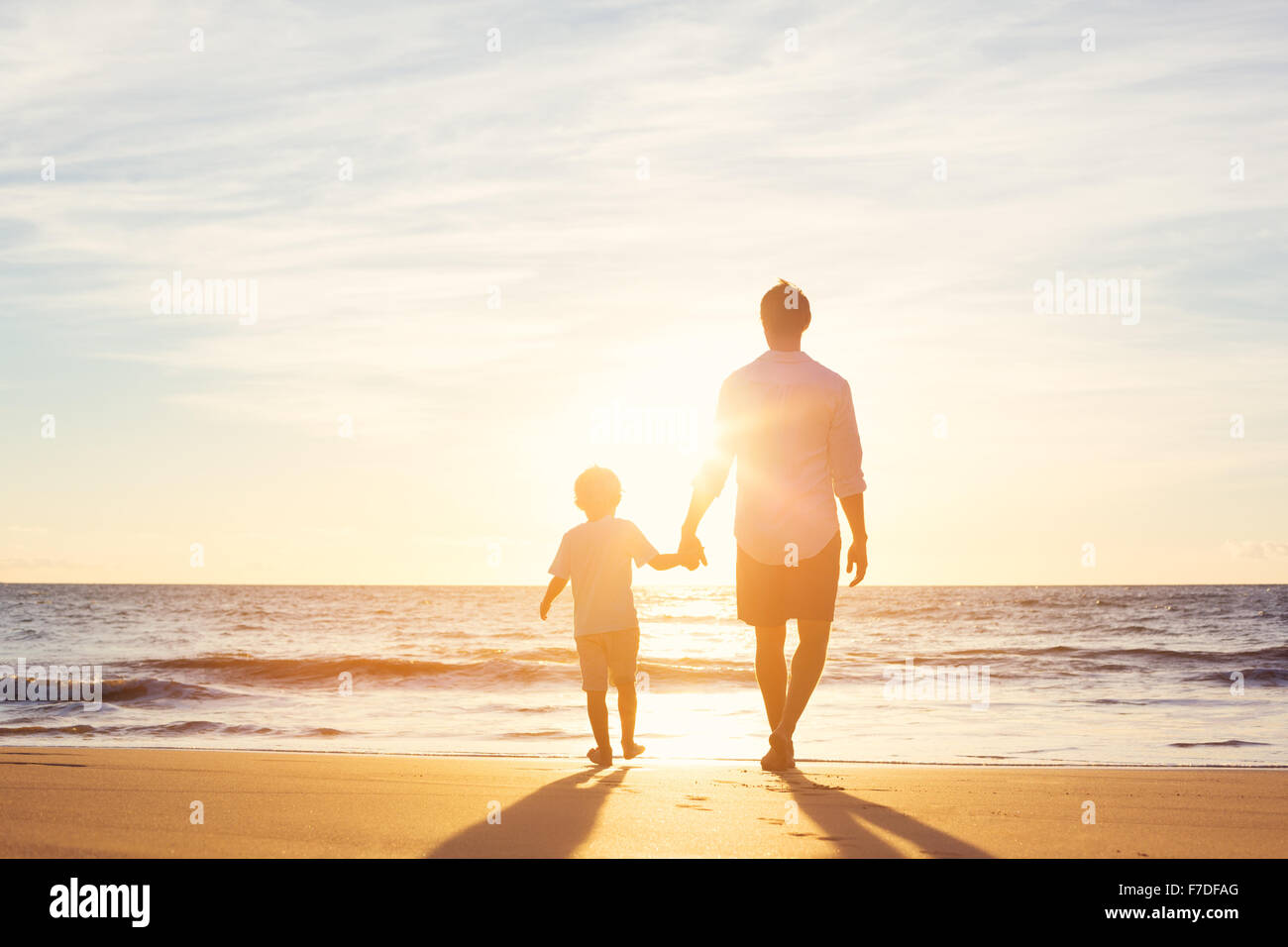 Father and Son Walking Together on the Beach at Sunset. Fatherhood Family Concept Stock Photo