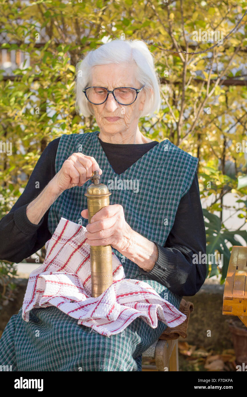 Grandma grinding coffee on a vintage wooden coffee grinder Stock Photo
