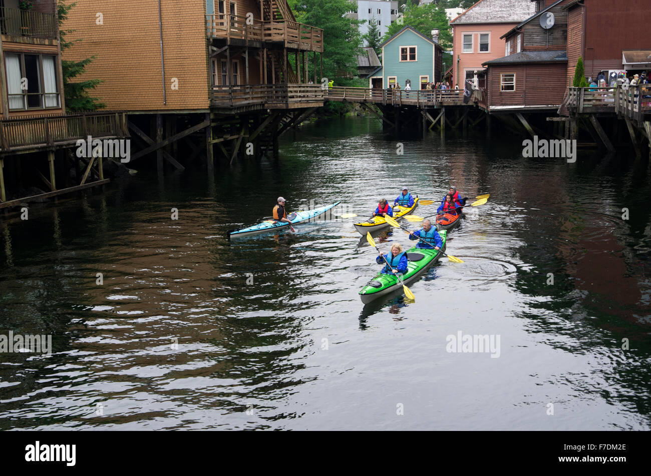 3 Kayaks, 6 paddlers, and one guide voyage into creek along Creek Street stores. Stock Photo