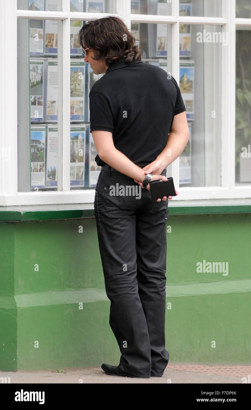 A male buy to let house buyer looks at properties on display in an estate agents window in Cowbridge, Wales, UK. Stock Photo