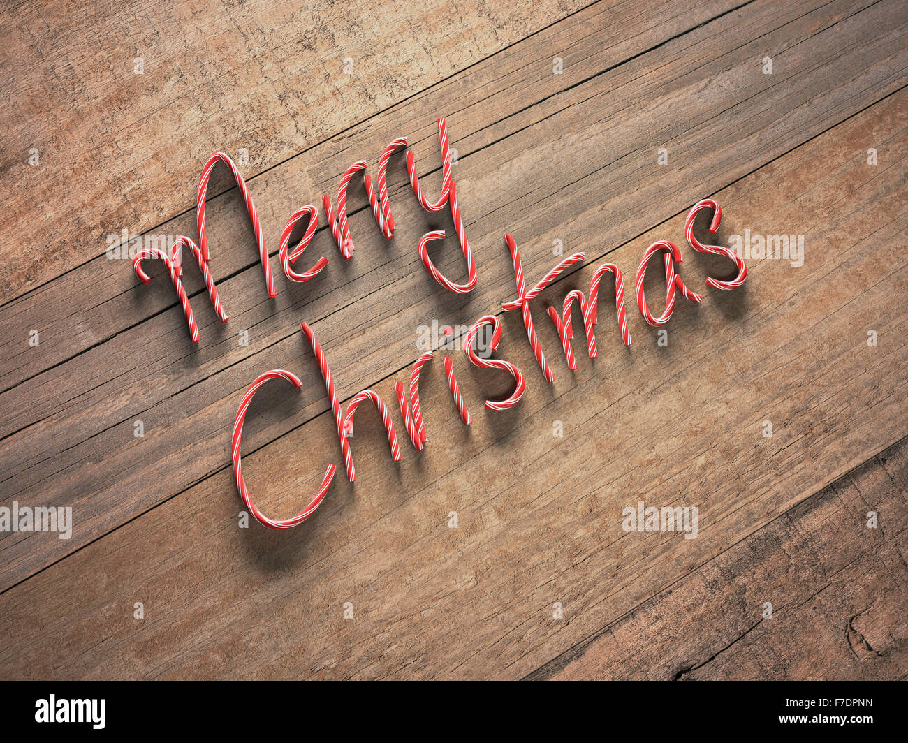 Merry Christmas written in red and white candy on an old wooden table. Depth of field applied with focus on center of the image. Stock Photo