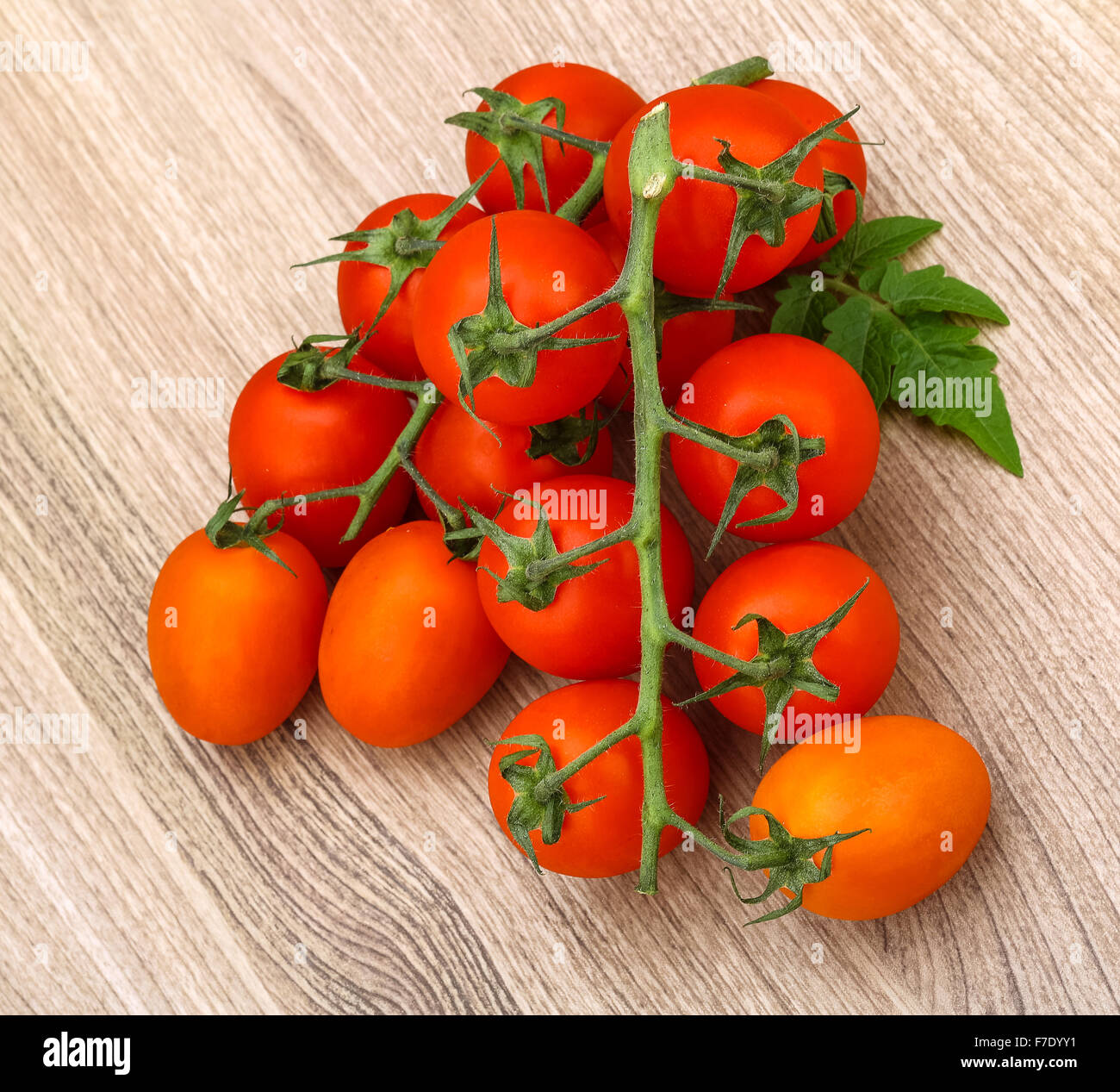 Tomatoes branch with leaf on the wood background Stock Photo - Alamy