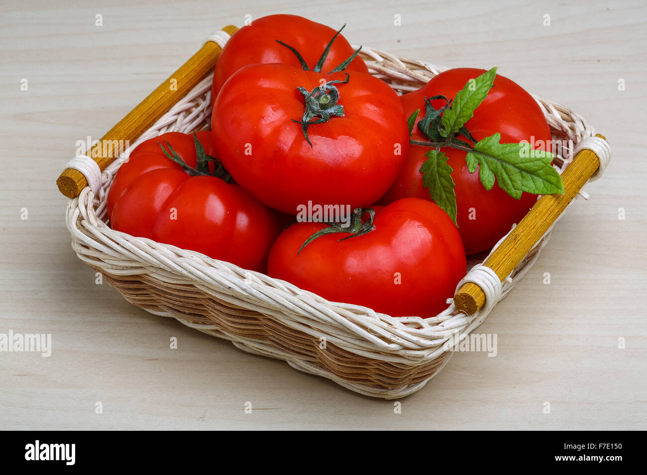 Red tomatoes in the basket with green branch Stock Photo - Alamy