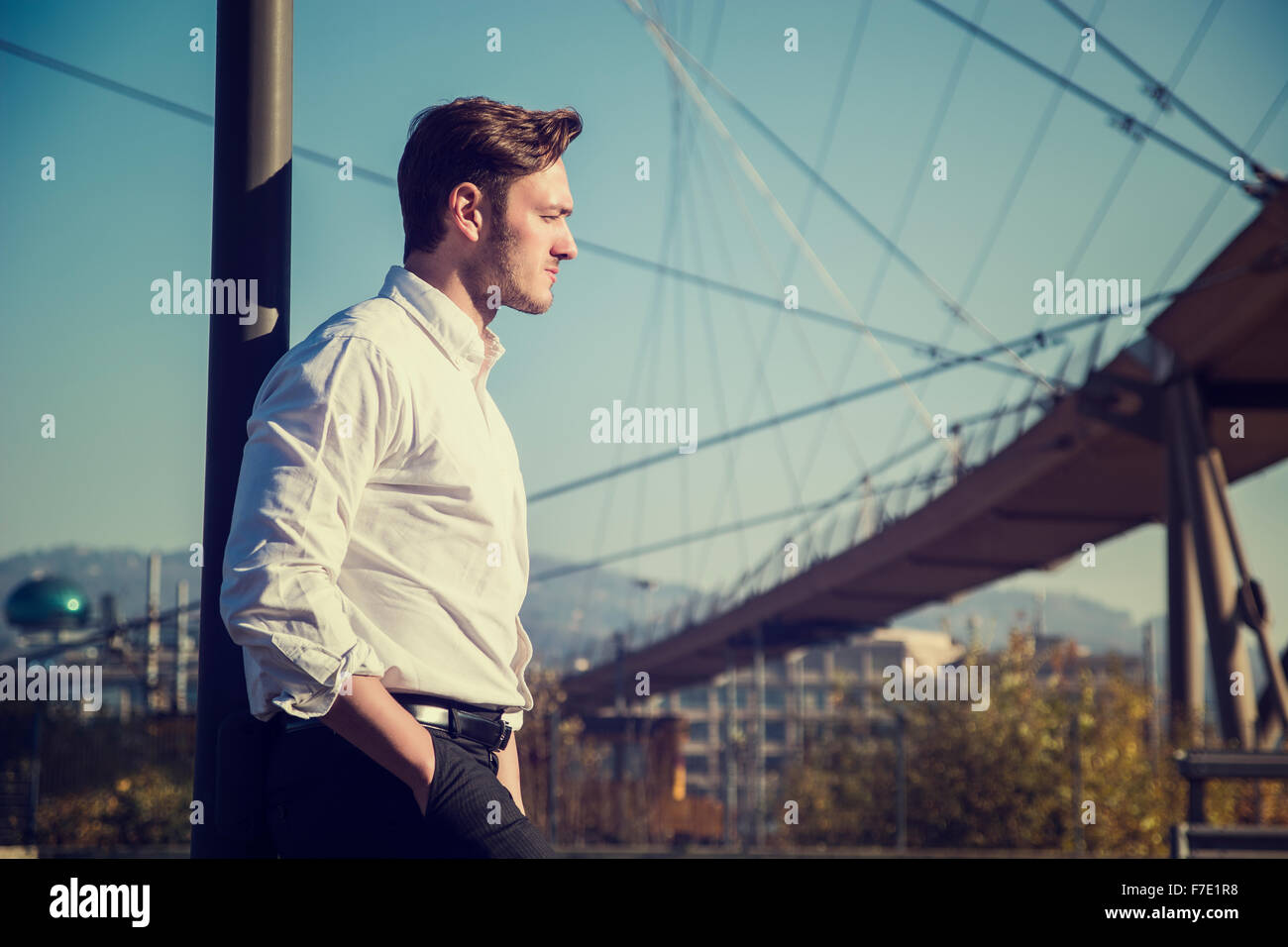 Handsome young man outside wearing white shirt, looking to a side ...