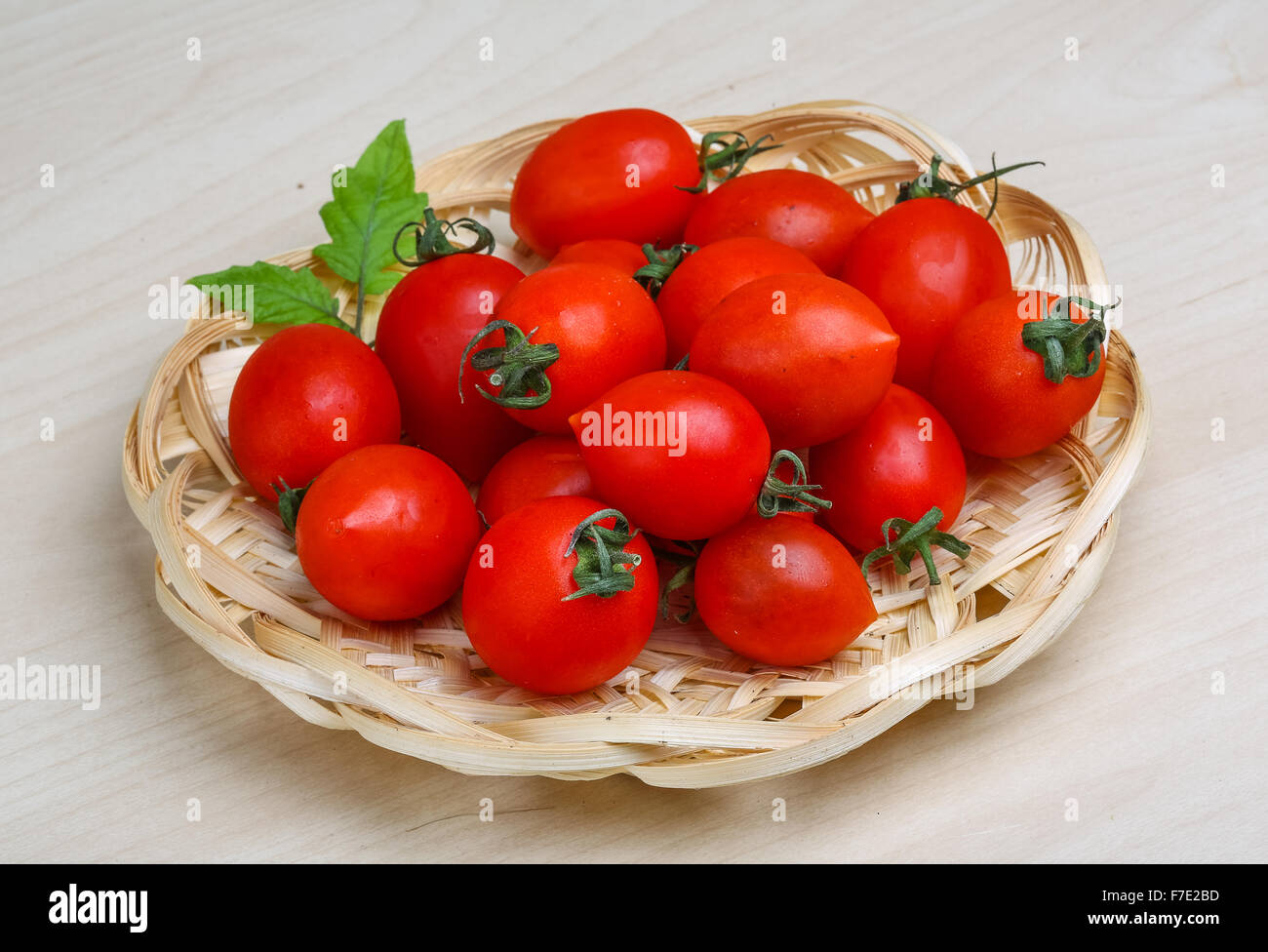 Cherry tomatoes in the basket with fresh green leaf Stock Photo - Alamy