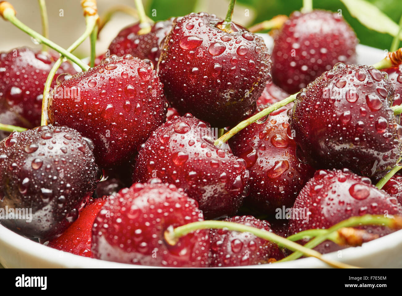 Cherries in white bowl on wooden table in garden Stock Photo