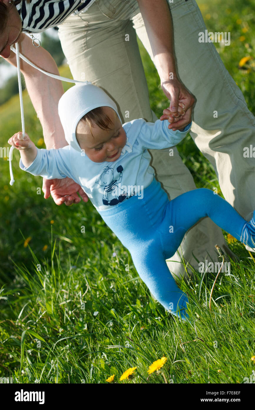 One year old baby learning to walk by holding his mother's hands Stock