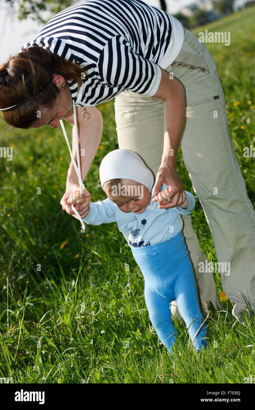 One year old baby learning to walk by holding his mother's hands Stock