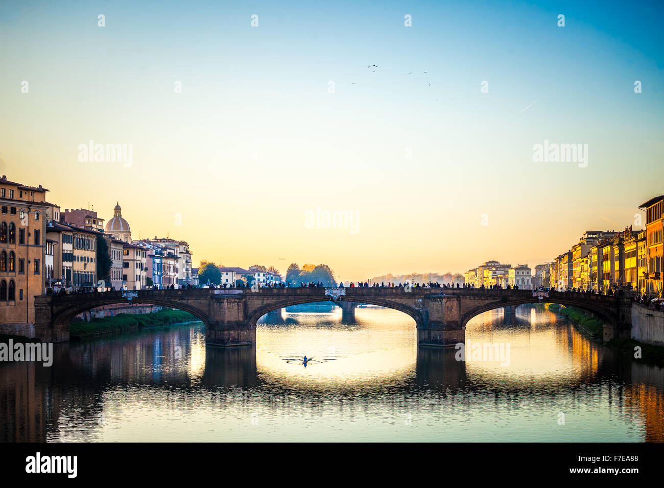 The amazing Ponte Vecchio over Arno River in Florence, Italy. Under the bridge one guy rowing Stock Photo