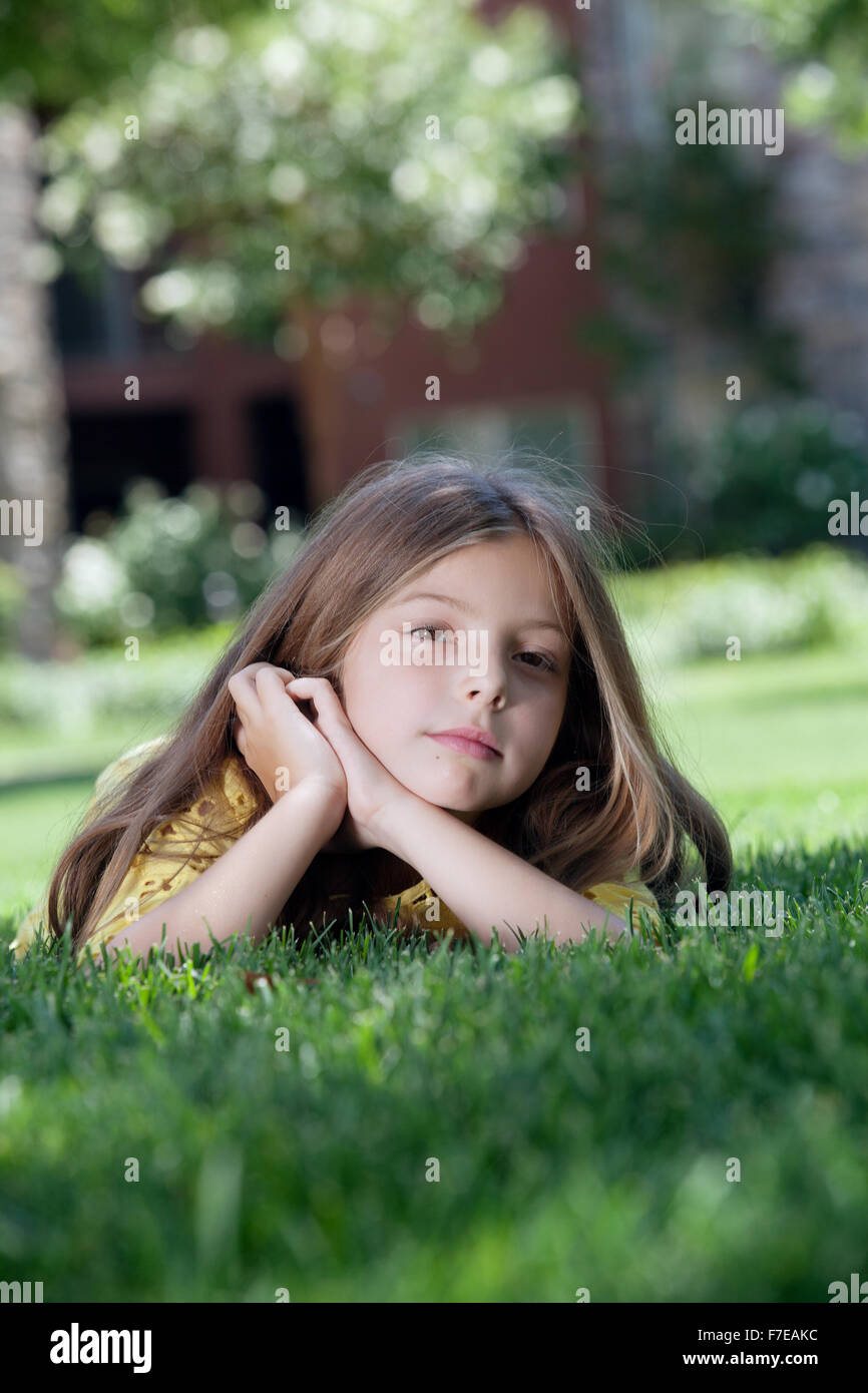 portrait of little girl laying on the grass in summer environment Stock ...
