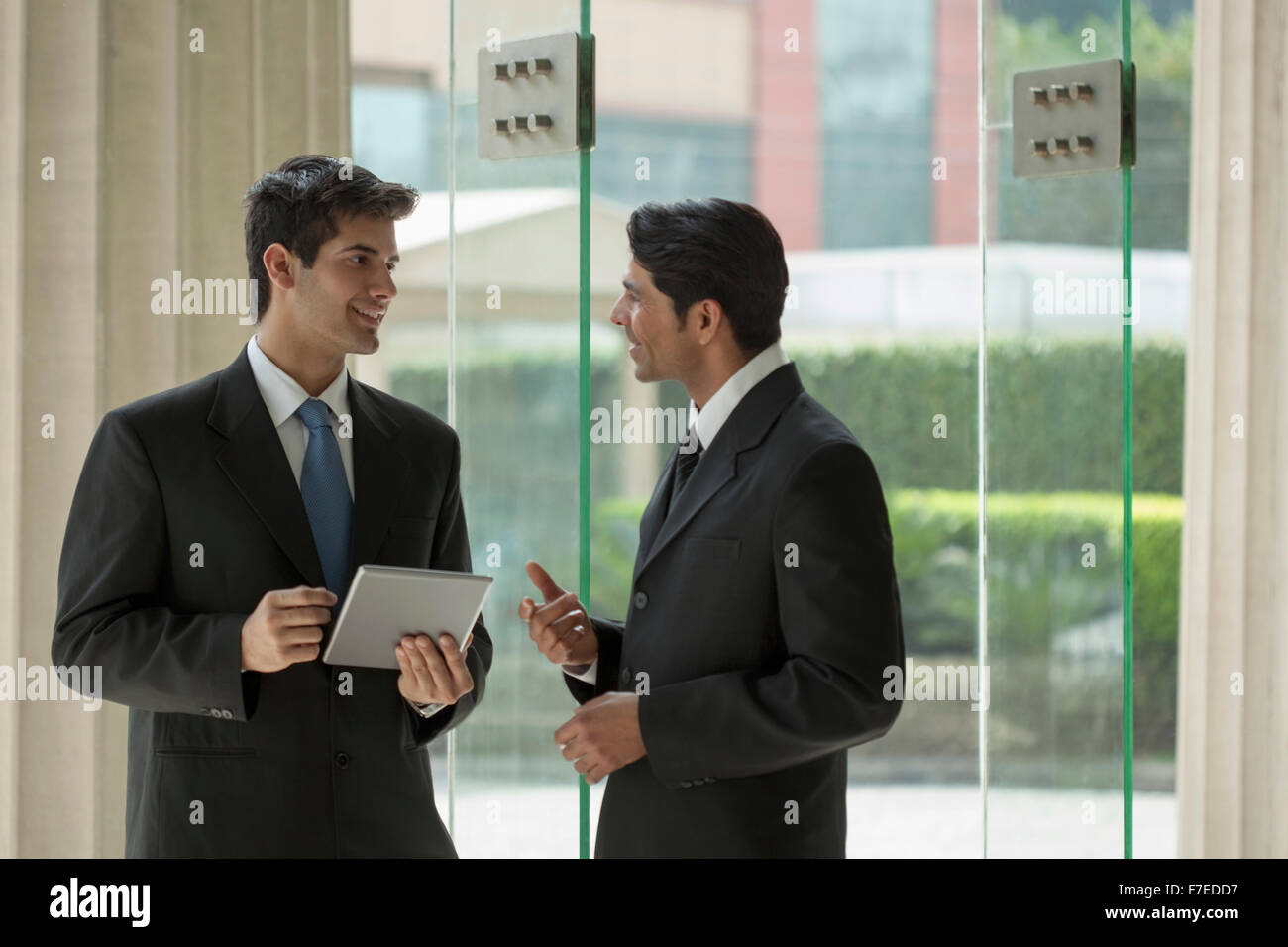 India, Two businessmen talking in office lobby Stock Photo - Alamy