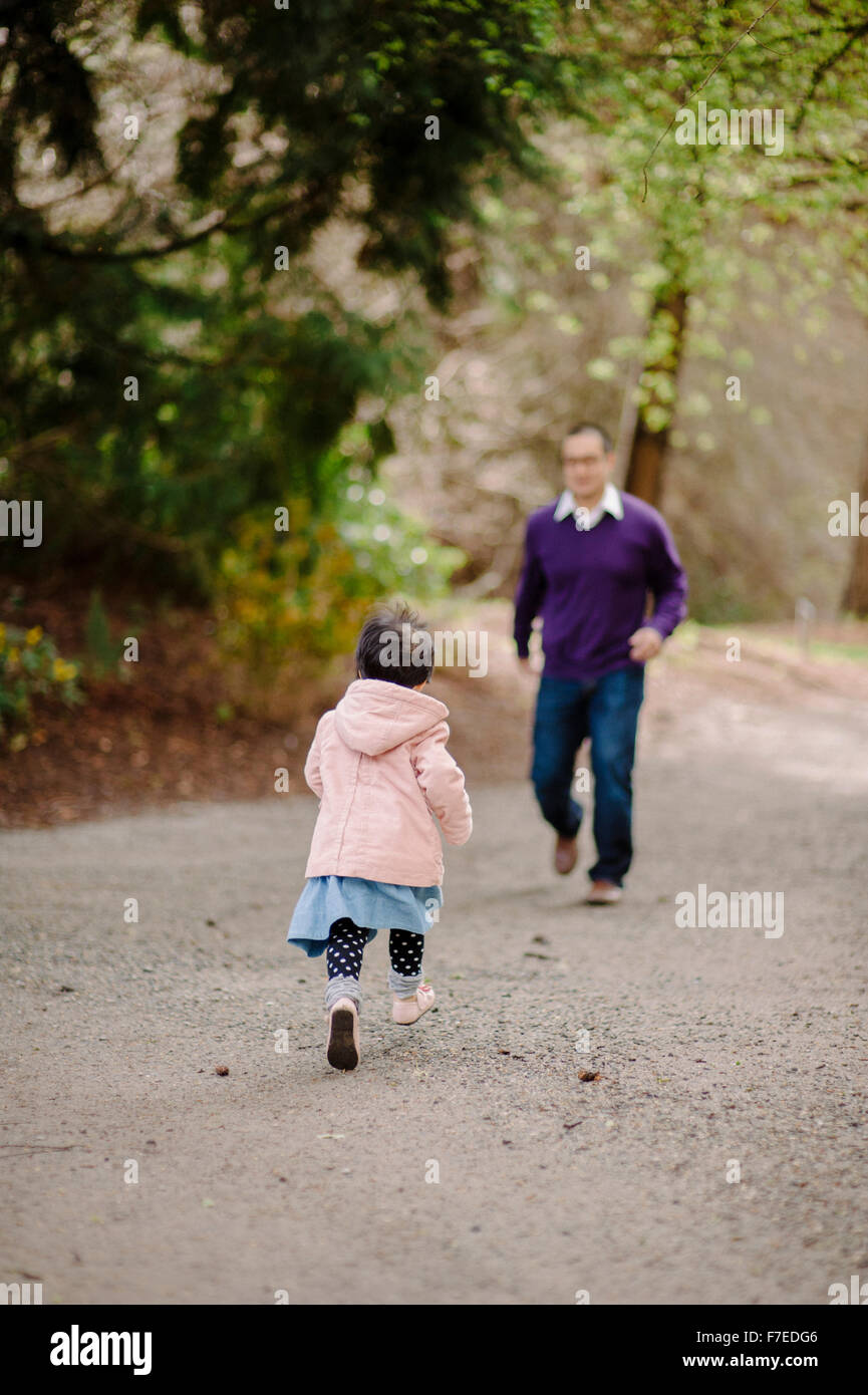 USA, Daughter (2-3) running towards father in park Stock Photo