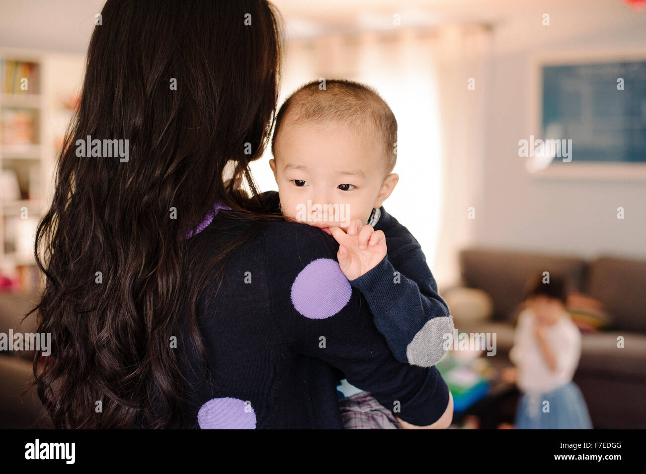 USA, Young woman carrying son (2-3) in living room Stock Photo