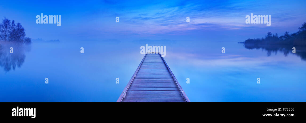 A small jetty on a still lake on a quiet morning at dawn, near Amsterdam in The Netherlands. Stock Photo