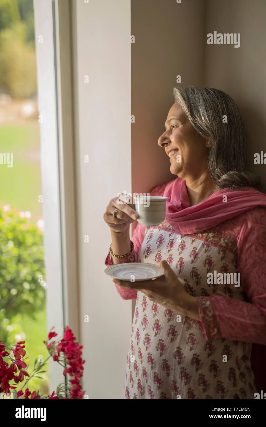 Mature woman at window with tea cup Stock Photo