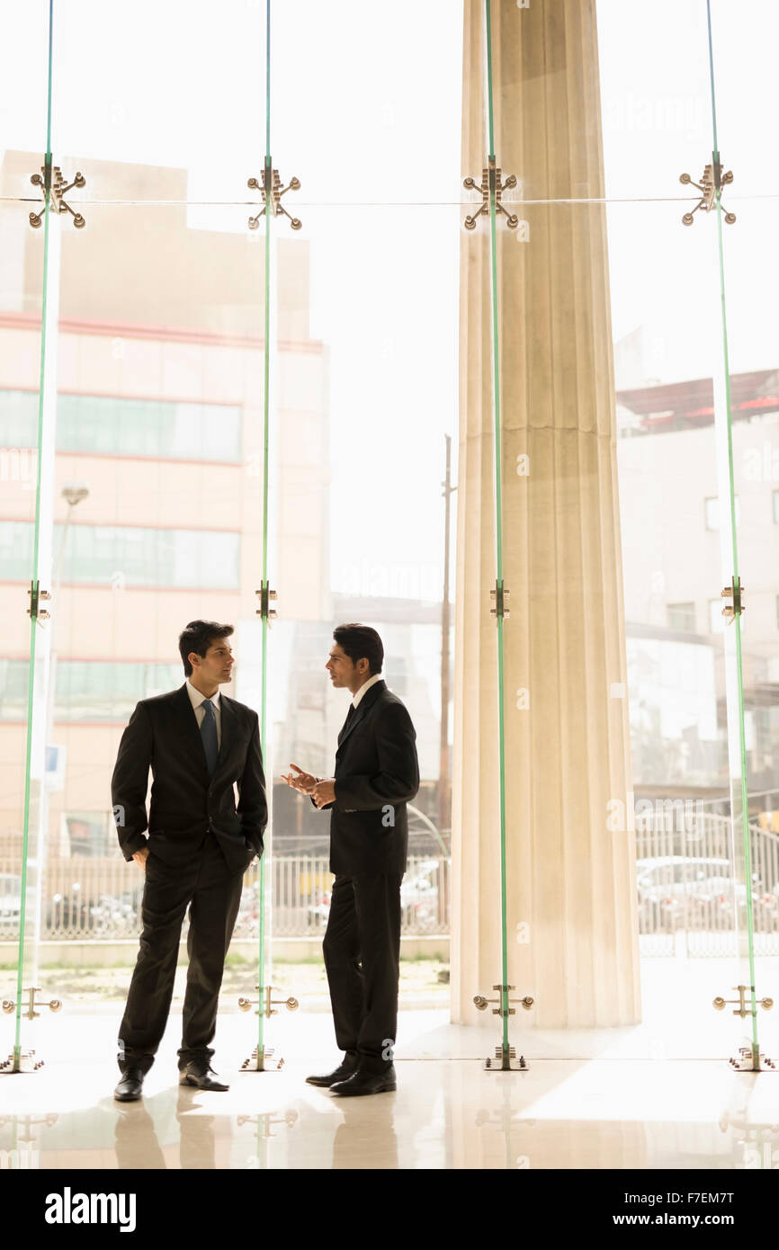 India, Two businessmen in suits talking in glass office lobby Stock ...