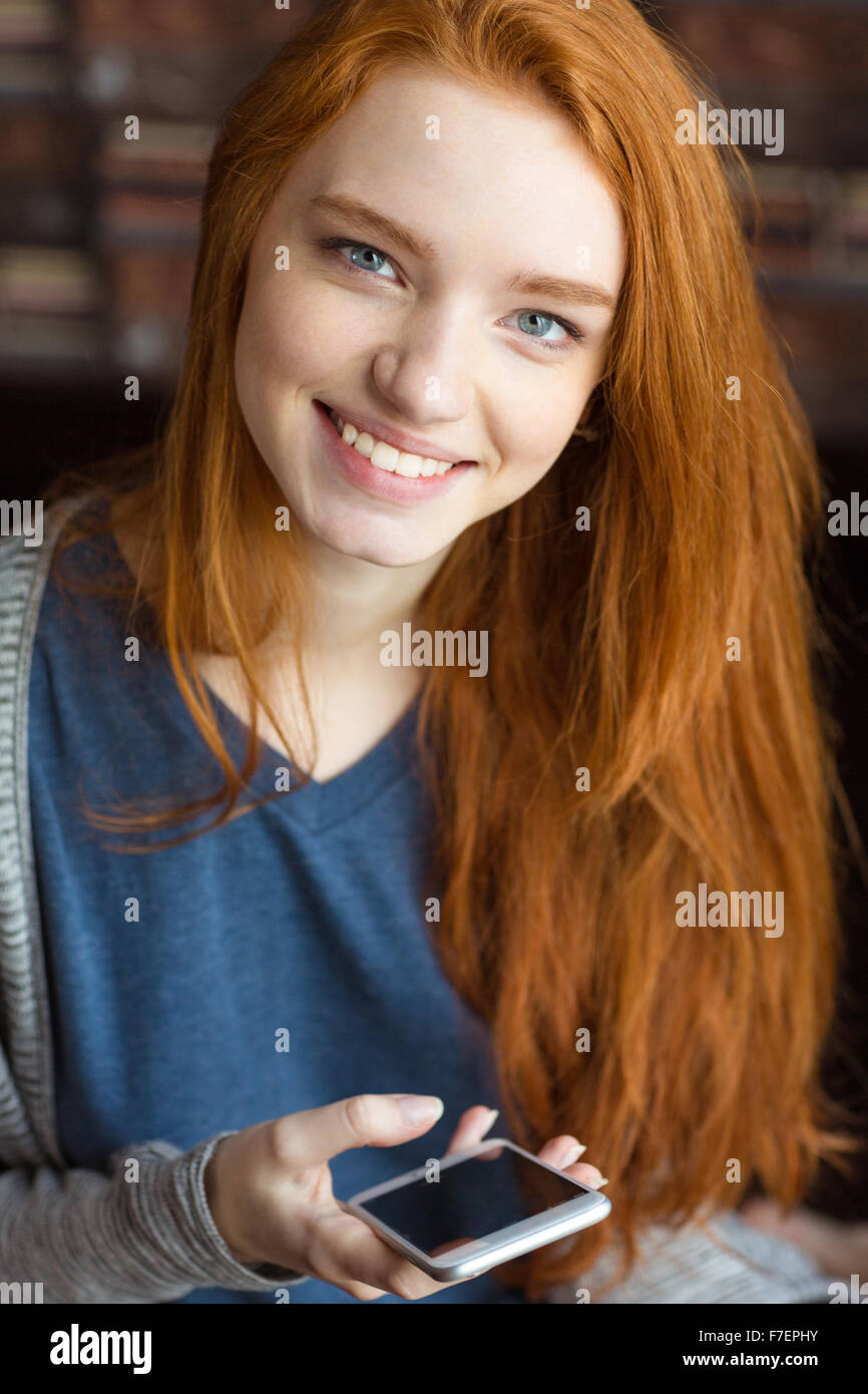 Portrait of happy smiling beautiful girl with long red hair using ...