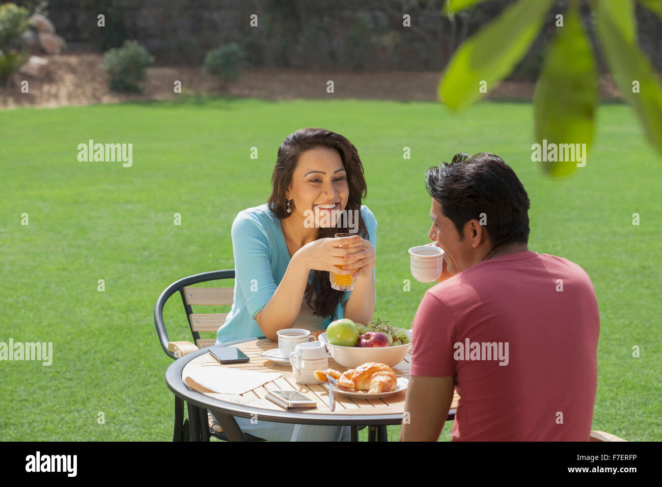 India, Woman holding glass of juice and talking to man at breakfast ...
