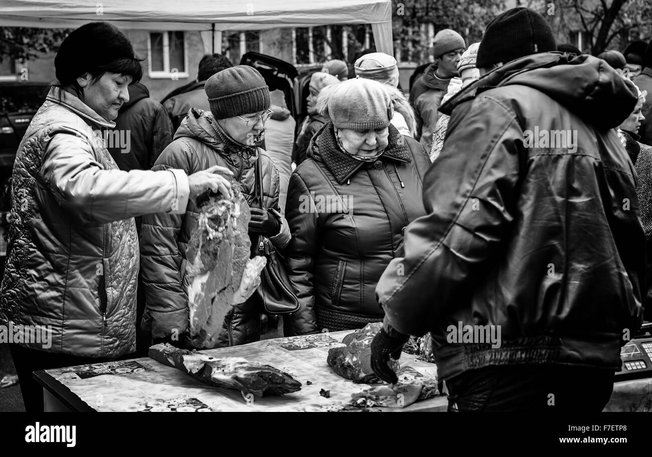 Three elderly Russian women inspecting and buying meat at a local farmer's meat market in Russia Stock Photo