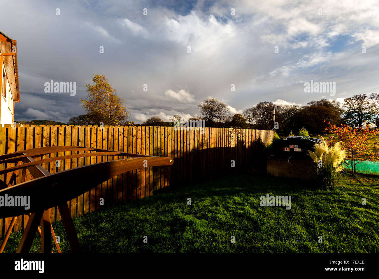sun shining through the clouds into a garden with wooden fence Stock ...