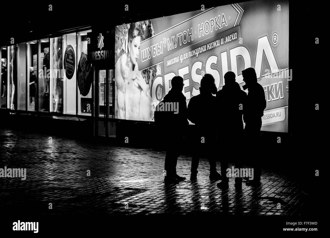 Group of Russia teenagers wait outside the Megapolis shopping and entertainment center in a light rain at night.  This photograp Stock Photo