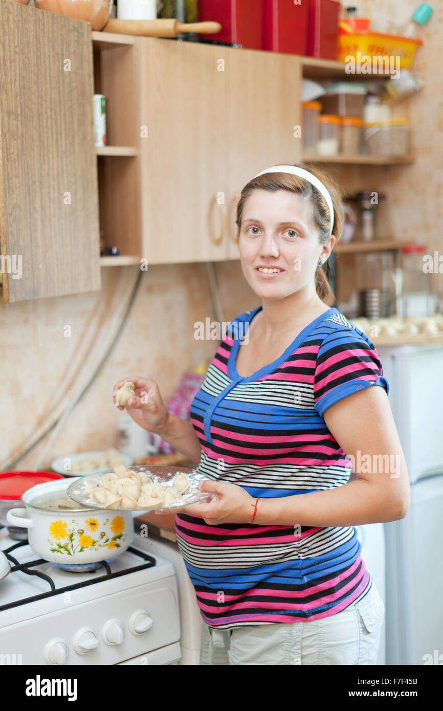 pregnant woman cooking dumplings in the pan on the stovetop Stock Photo