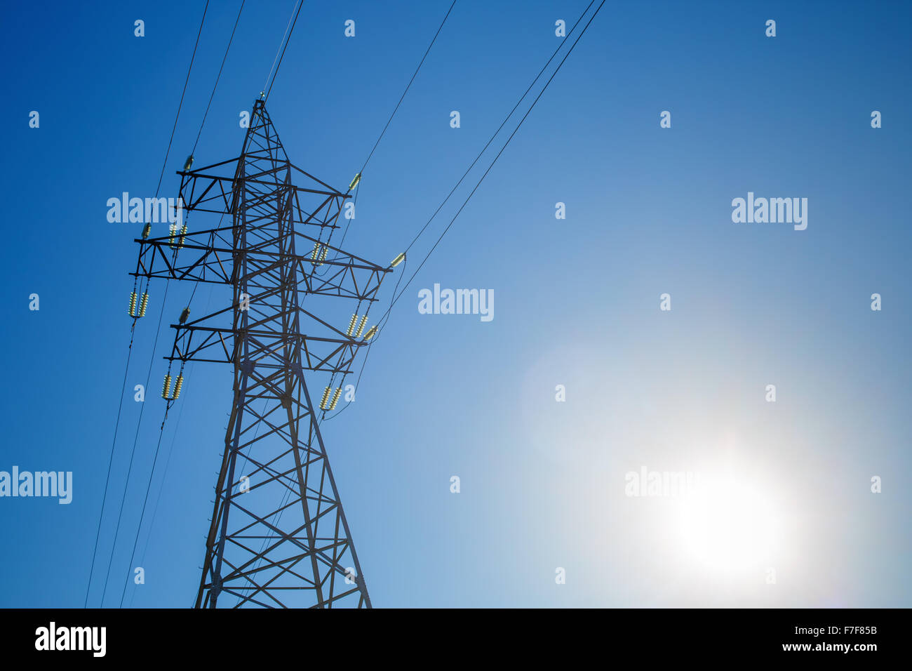 High voltage tower on blue sky background. Electricity transmission pylon. Stock Photo