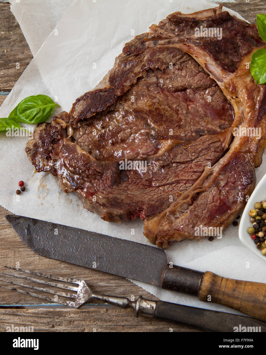 grilled beef steak with ground pepper and basil on wooden table Stock Photo