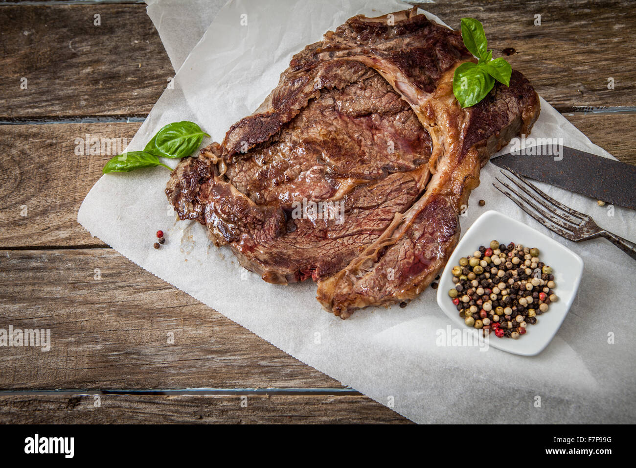 grilled beef steak with ground pepper and basil on wooden table Stock Photo