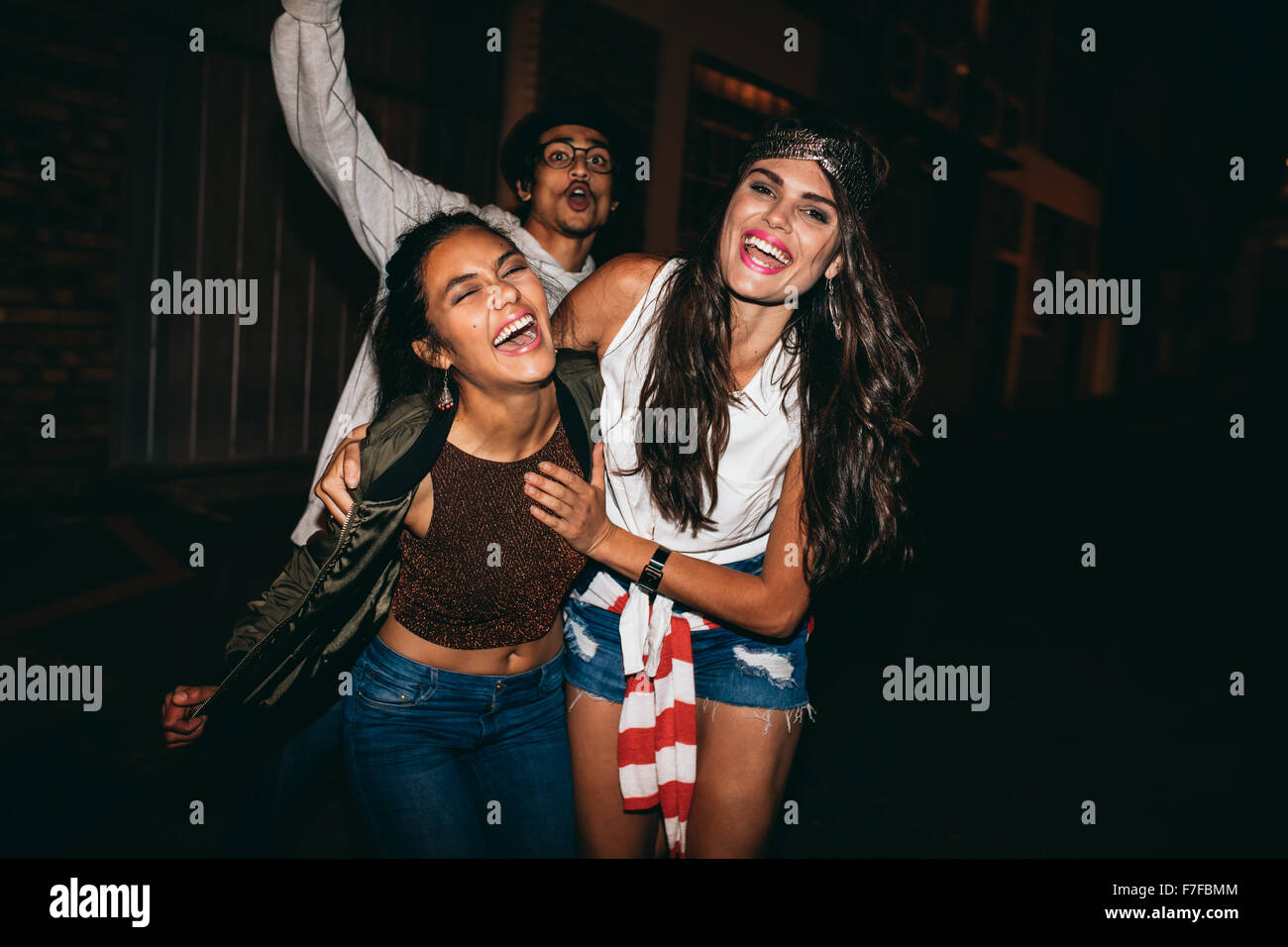 Portrait of three young friends having party outdoors. Cheerful young best friends hanging out at night. Stock Photo