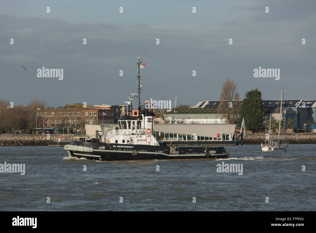 Tug boat heading out of Portsmouth harbour. White and black work boat preparing for the arrival of a container ship. Stock Photo
