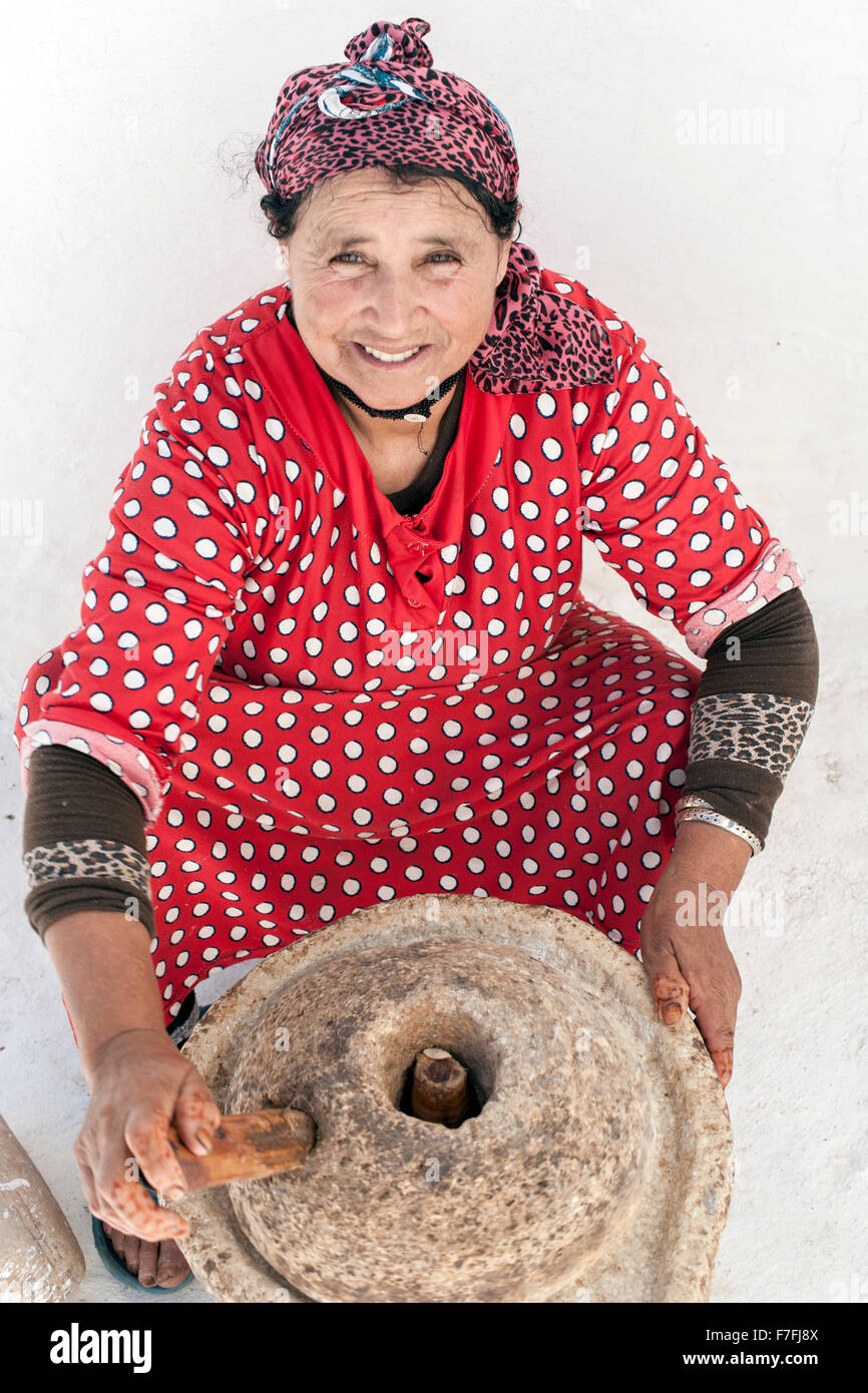 Moroccan woman pressing argan nuts for oil. Stock Photo