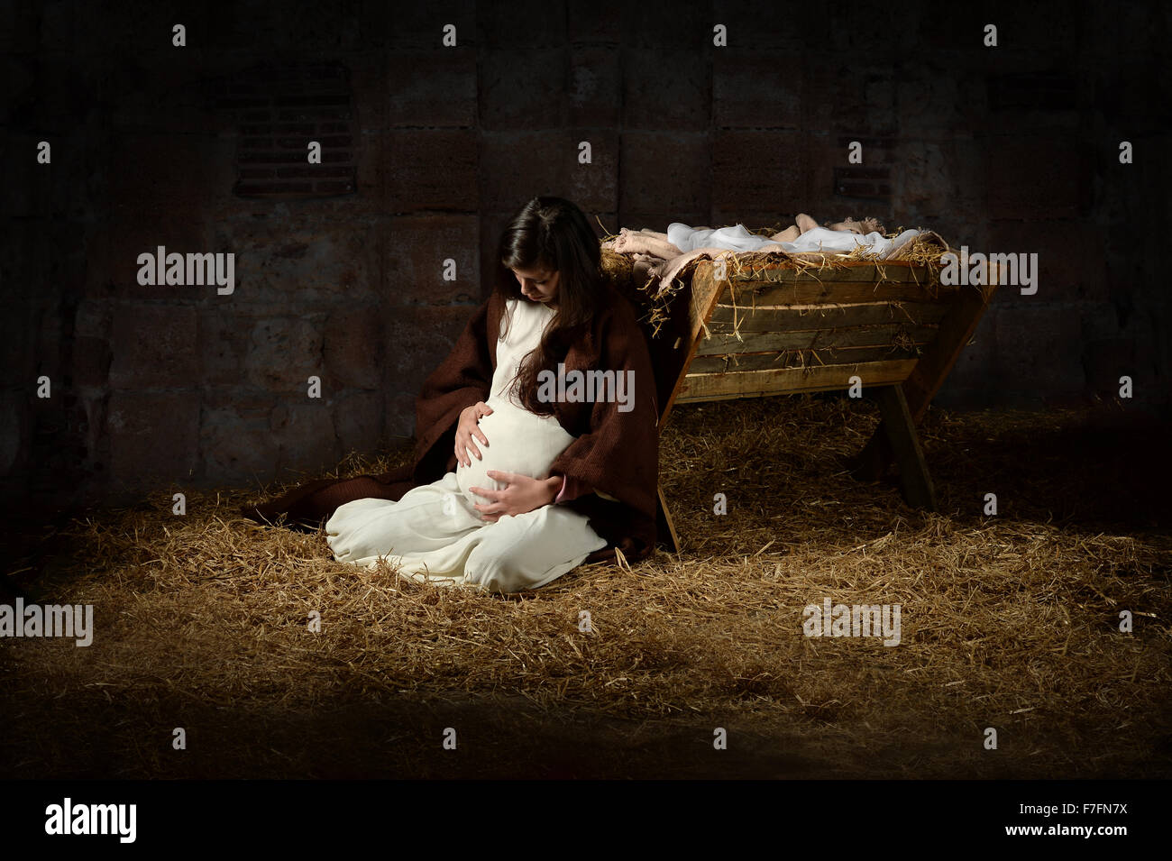 Pregnant Mary leaning on the manger on Christmas Eve Stock Photo