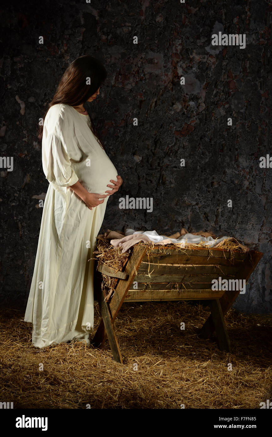Pregnant Mary contemplating in front of the manger Stock Photo