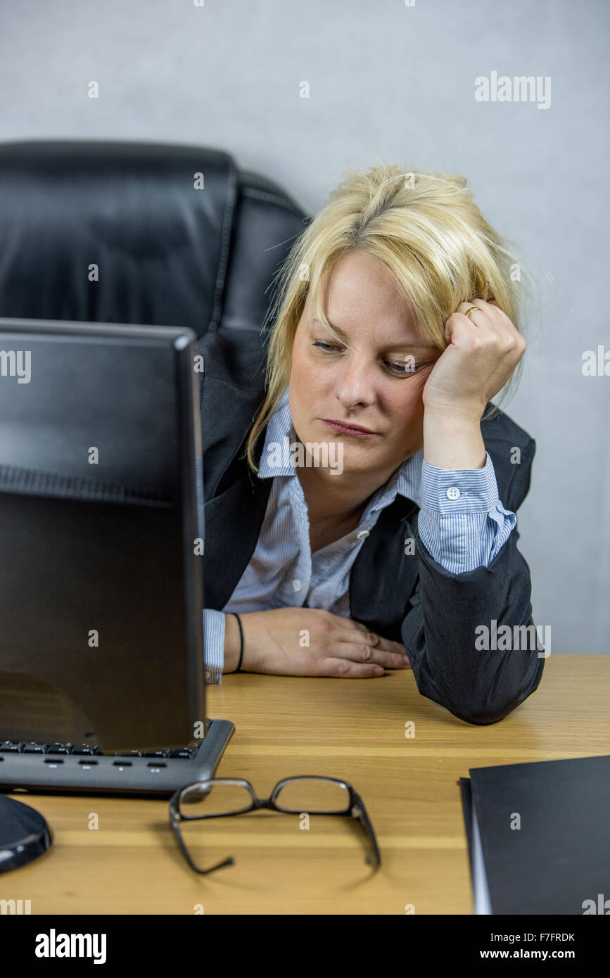 A Female office worker sitting at her desk on her 9 to 5 job Stock