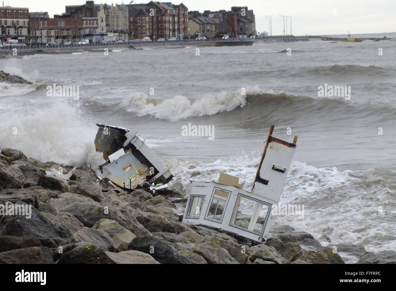 Morecambe, Lancashire, UK. 30th November, 2015.   In the aftermath of the weekends storms the remains of fishing boat lay on the sea defences on Morecambe Promenade, after the biat broke its moorings and was broken up on the rocks in the during the storms that ravaged the UK  over the week end Credit:  David Billinge/Alamy Live News Stock Photo