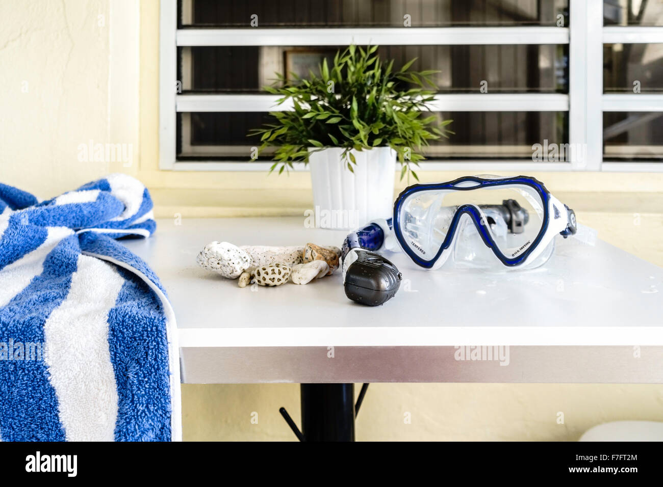 A wet snorkel and mask and a beach towel lies on a table with a collection of beach rocks. St. Croix, U.S. Virgin Islands. Stock Photo