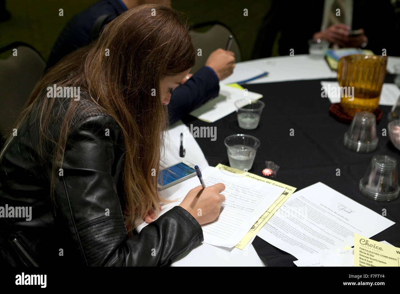 Young woman filling out an application at job recruiting fair