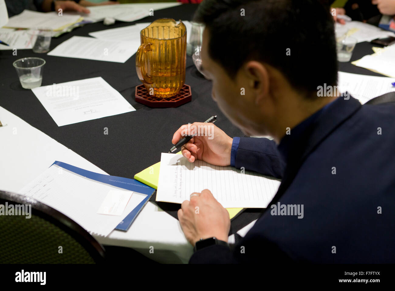 Young Asian man filling out an application at job recruiting fair - Arlington, Virginia USA Stock Photo