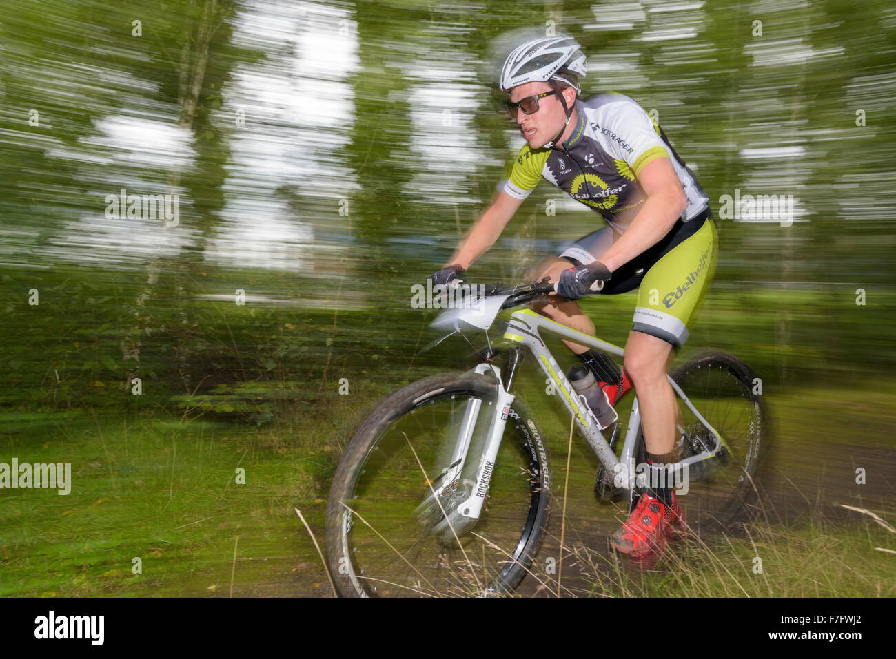 A mountain biker rides through a forest at a mountain biking competition Stock Photo