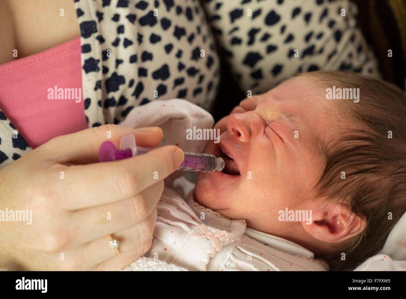 mum giving baby medicine with a syringe Stock Photo