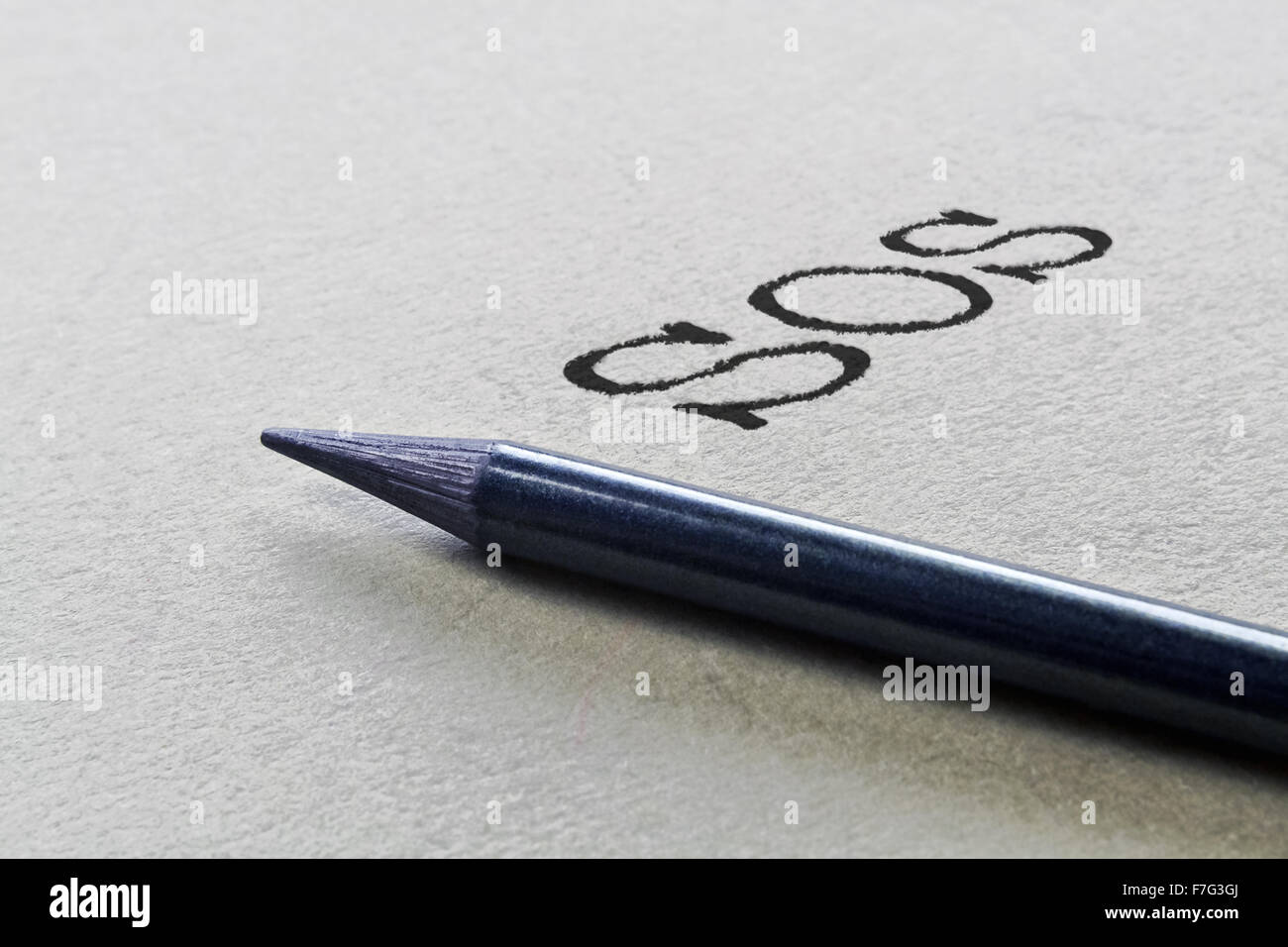 Graphite pencil and handwritten abbreviation SOS for help Stock Photo
