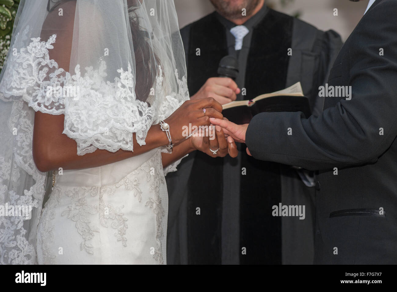 Bride placing ring on grooms finger Stock Photo