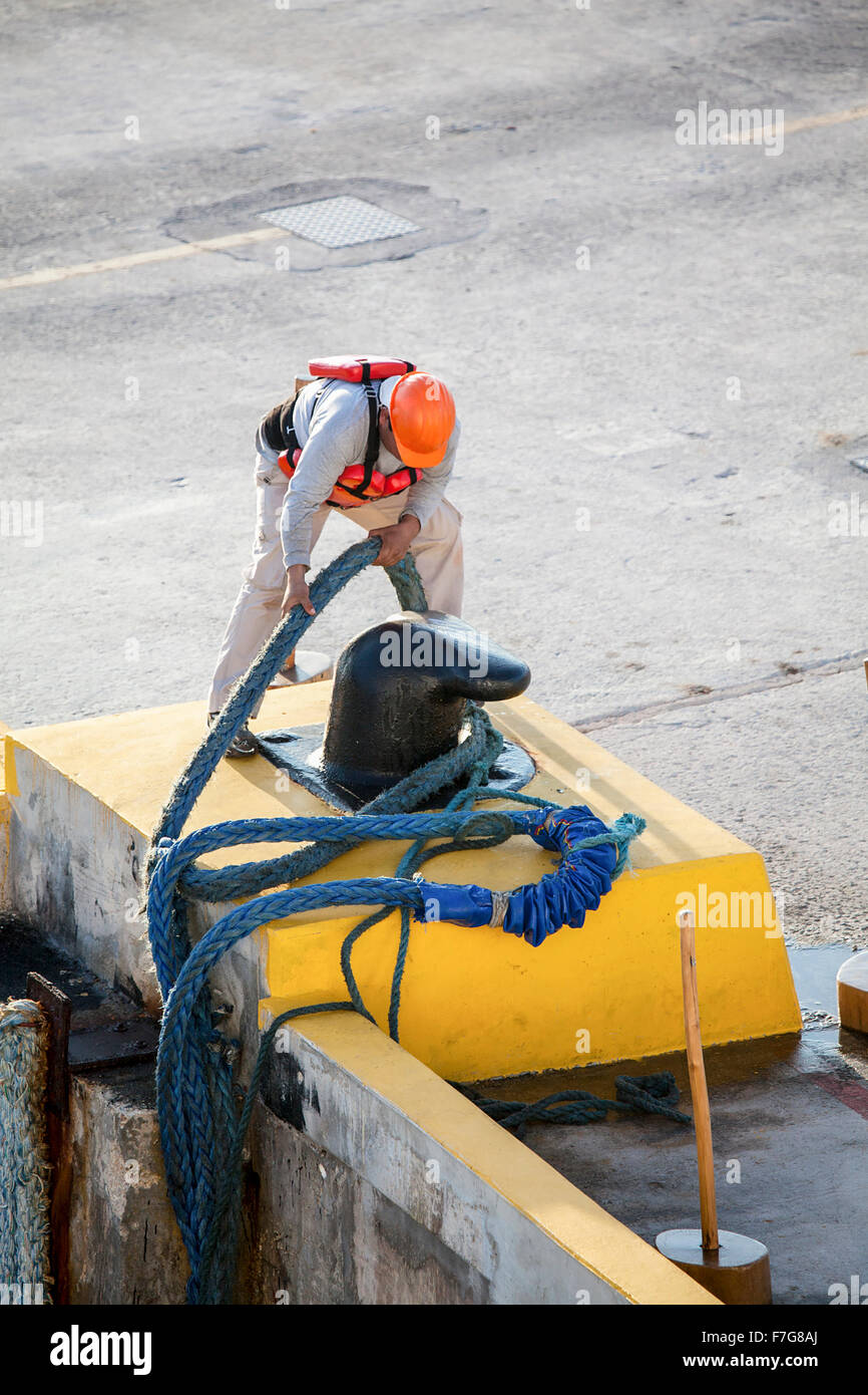 Mexican Latino dock workers tie off ship mooring lines. Stock Photo