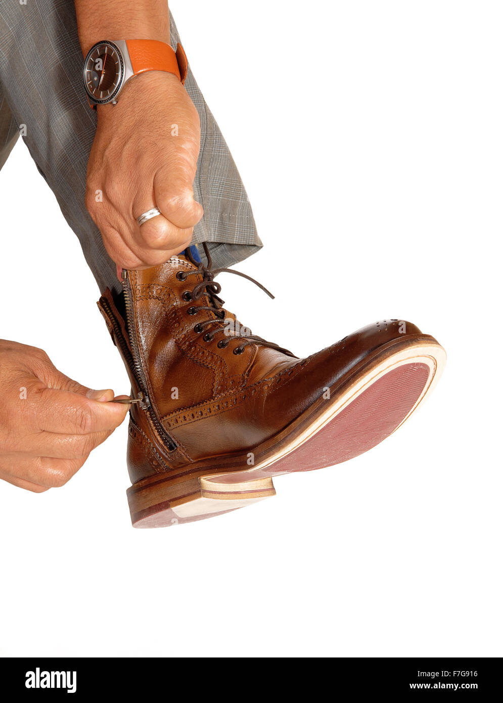 A closeup image of a man putting on his brown boots, pulling up the zipper  of the shoe, isolated for white background Stock Photo - Alamy