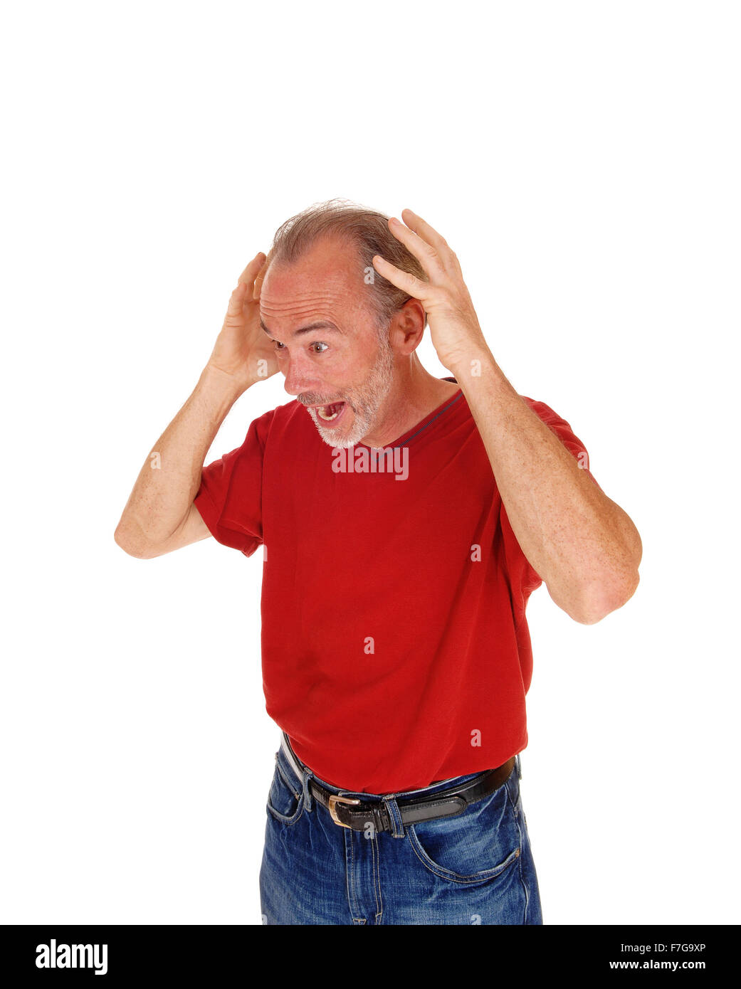 A older man in a red t-shirt and jeans standing with his hands on his ...