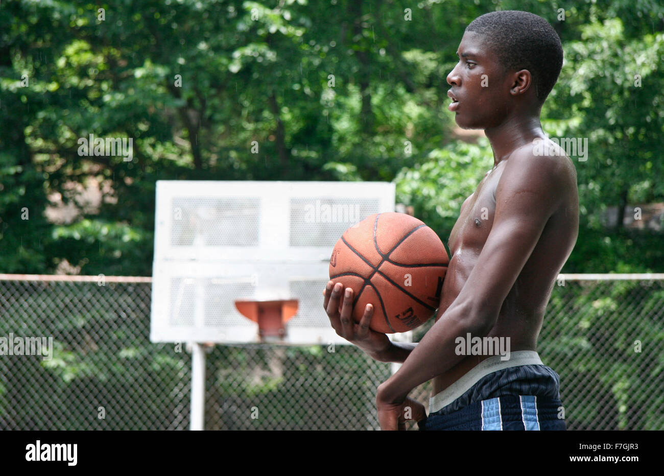 NEW YORK CITY - JUNE 22: Two black boys playing in one Harlem basketball court, chain-link fence boxes, seen on June 22, 2008 in Stock Photo