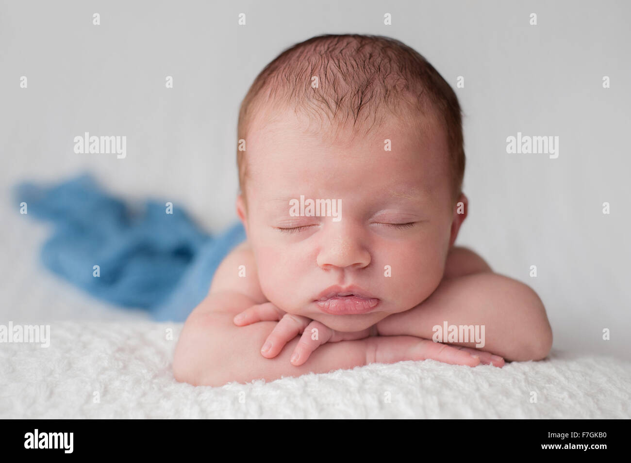A sleeping, three week old, newborn baby boy swaddled in a gauzy blue