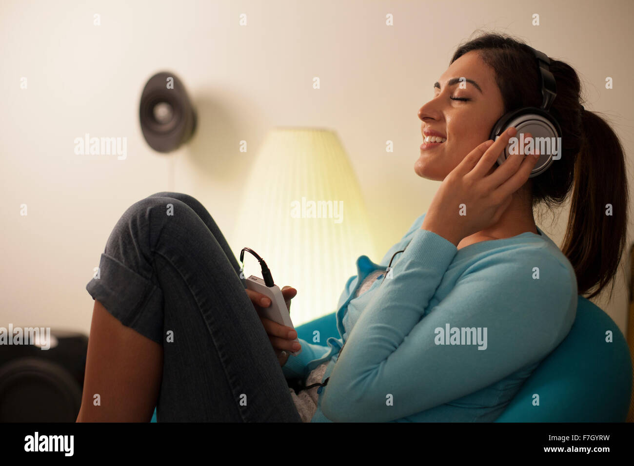 Singapore, Young woman listening to music in living room Stock Photo ...